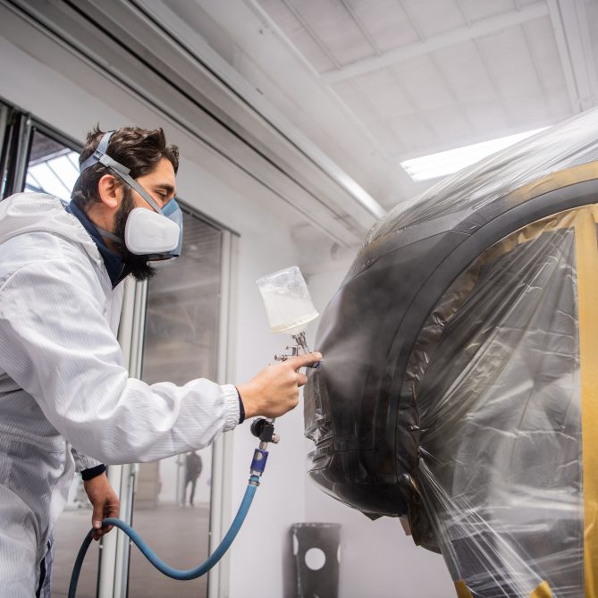 Image of a man spray painting a car body used on the Wondercar website